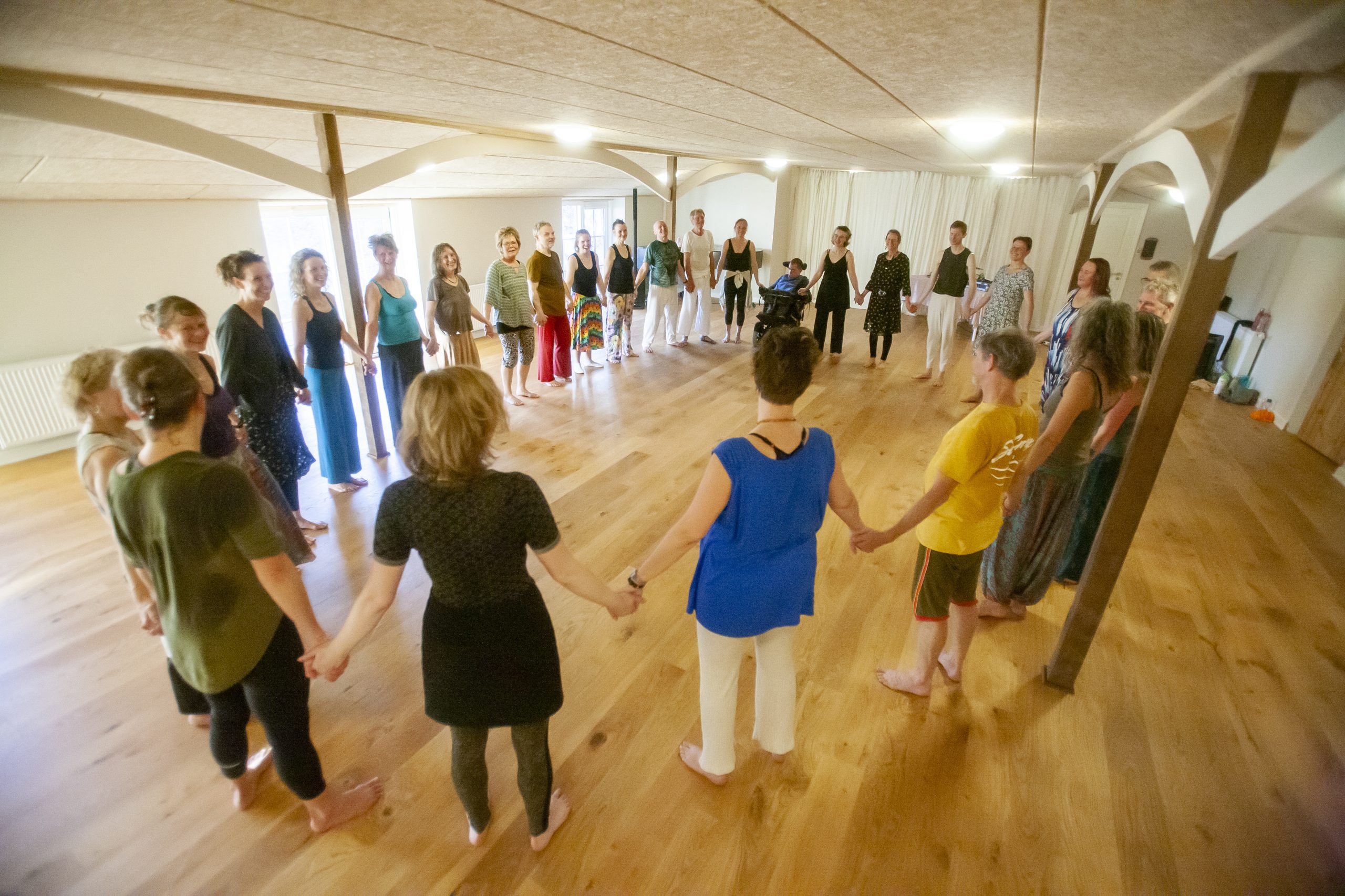 Gruppe mennesker som holder i hånd i en stor cirkel